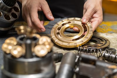 Professional mechanic man holding Valve plate of the hydraulic piston pump to inspection and repair Professional mechanic man holding Valve plate of the hydraulic piston pump to inspection and repair