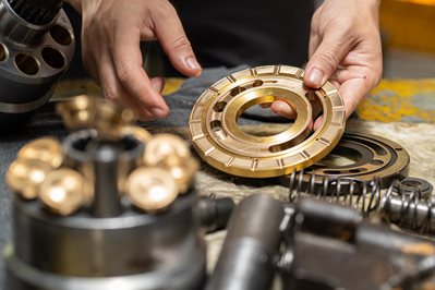 Professional mechanic man holding Valve plate of the hydraulic piston pump to inspection and repair