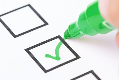 Human hand drawing green check mark in checklist