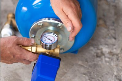 Blue metal tank of a pumping station with a pressure gauge.