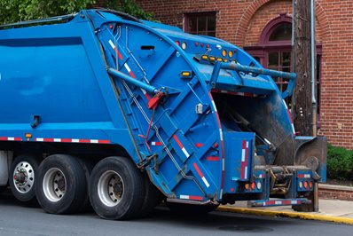 blue-garbage-truck-parked-on-street-near-brick-building.jpg Blue garbage truck parked on street near brick building.