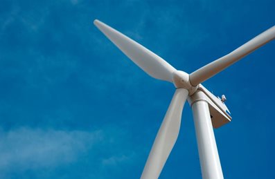 large-wind-turbine-with-rotating-blades-against-a-clear-blue-sky.jpg Large wind turbine with rotating blades against a clear blue sky.