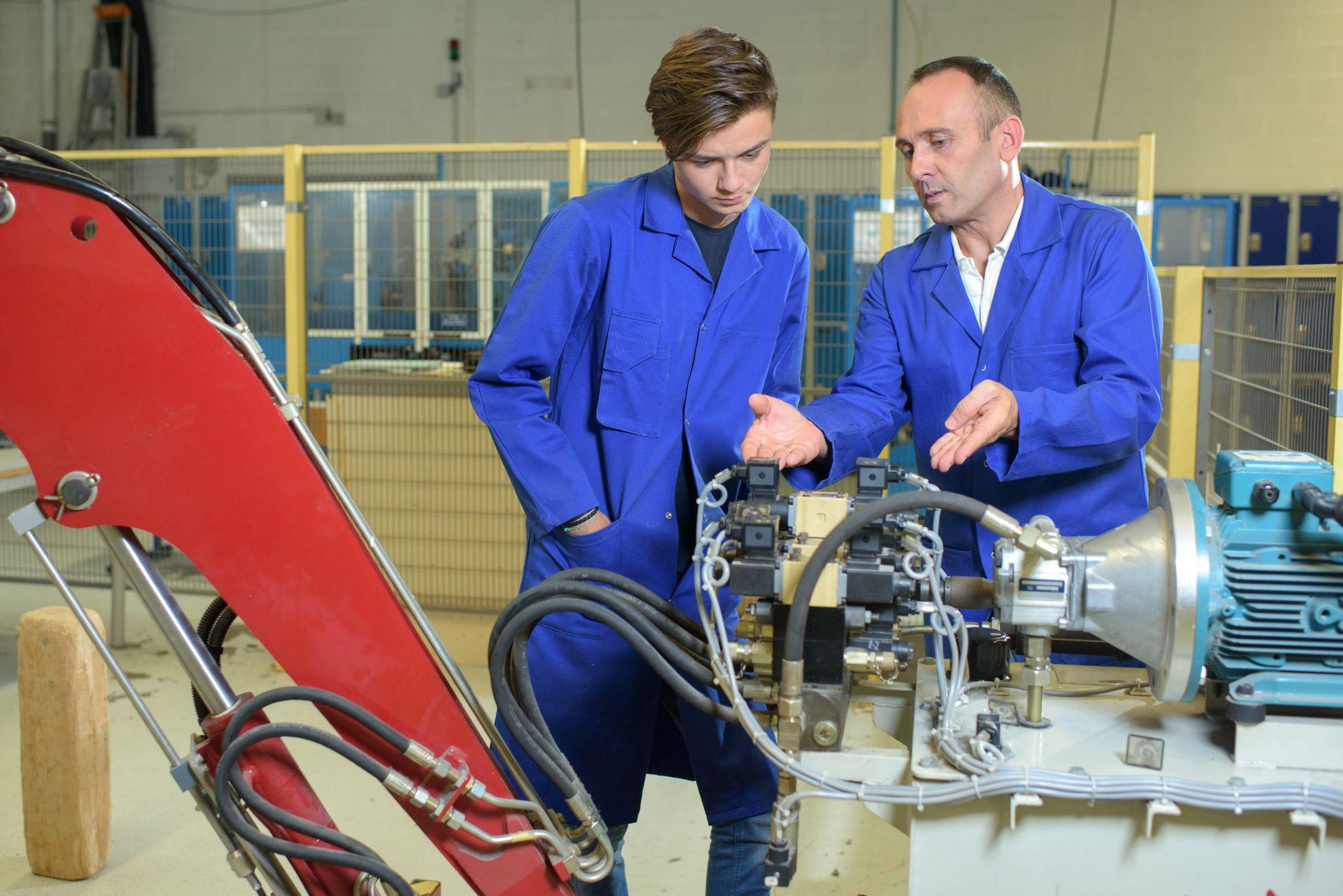 Engineers looking at hydraulic arm mechanicsm