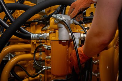 Low key photo of hydraulic pipes maintenance on heavy industry machine.